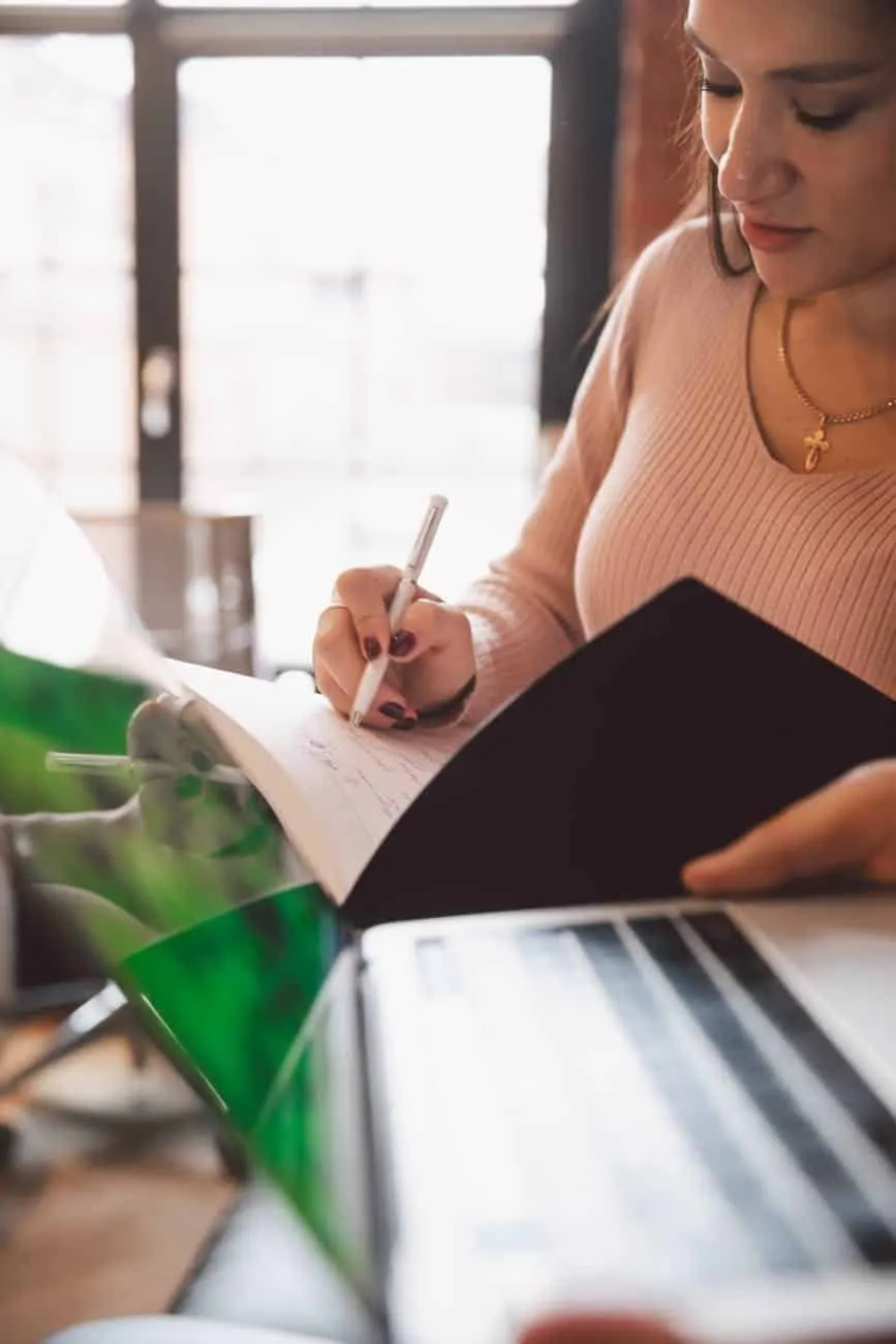 photo of woman writing on notebook, wish list for dream custom home