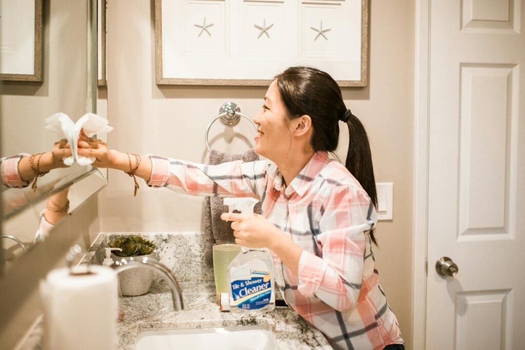 woman smiling while cleaning the mirror